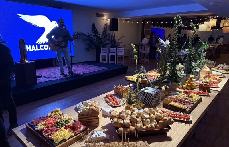 Mesa larga con canapés y un artista cantando