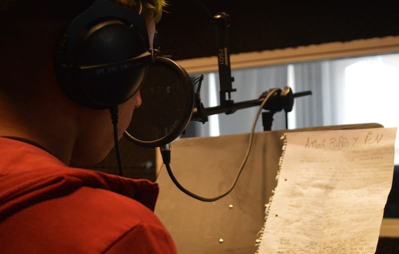 Joven con letra en el atril,cantando 